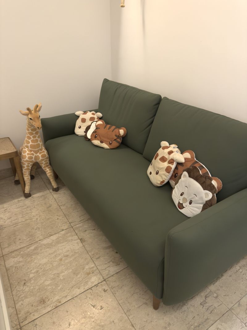 Sala de espera com sofá verde e bichos de pelúcia