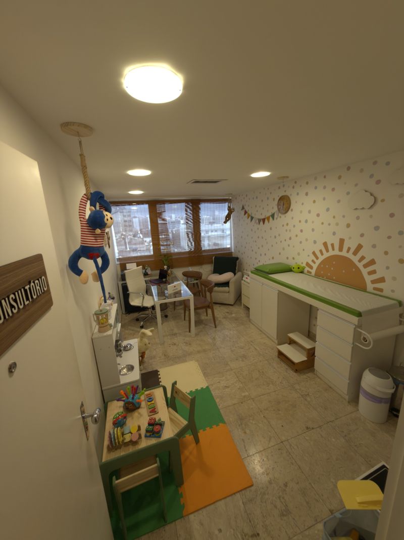 Consultório da Dra. Raizza: maca infantil, parede com sol e bolinhas, mesa e cantinho de brincar